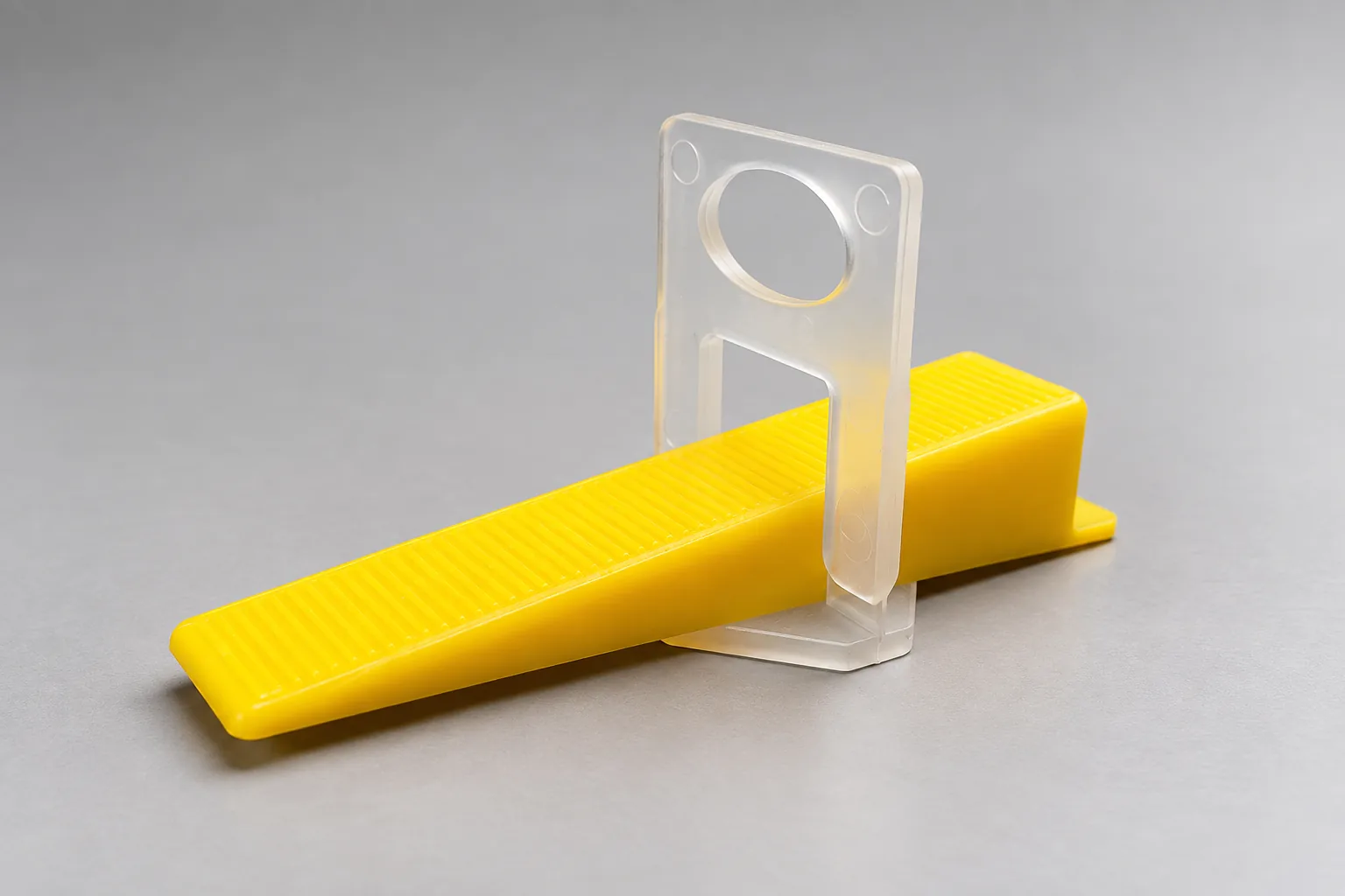 Clear tile leveling clip with a yellow ribbed wedge