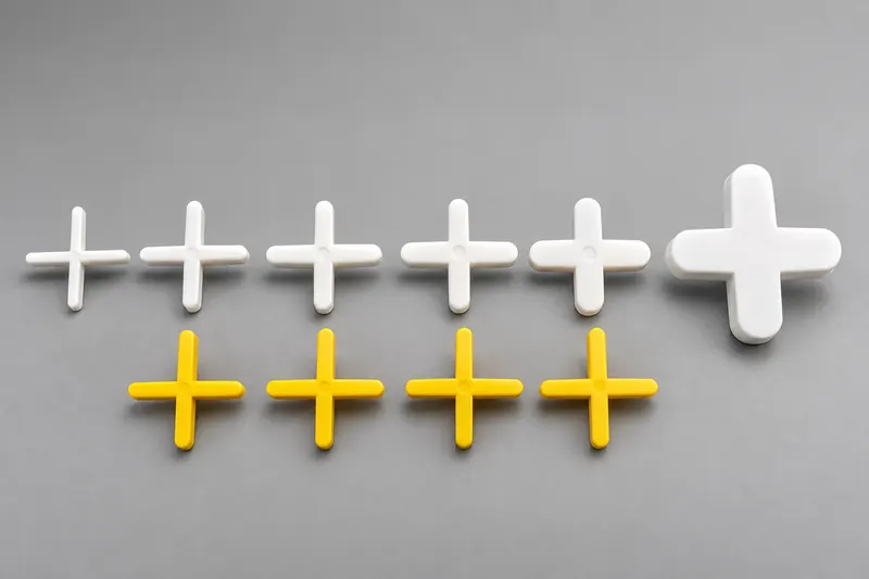 White and yellow cross tile spacers in several sizes on a gray surface